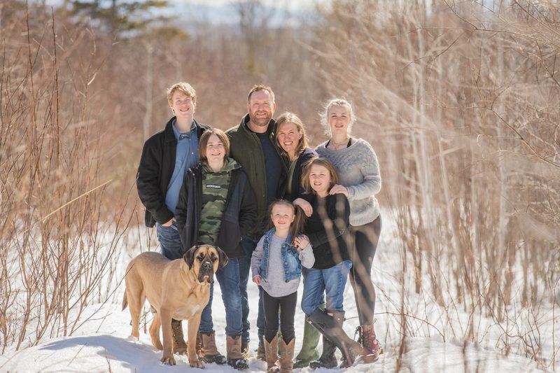A family of seven stands in the snow with their mastiff