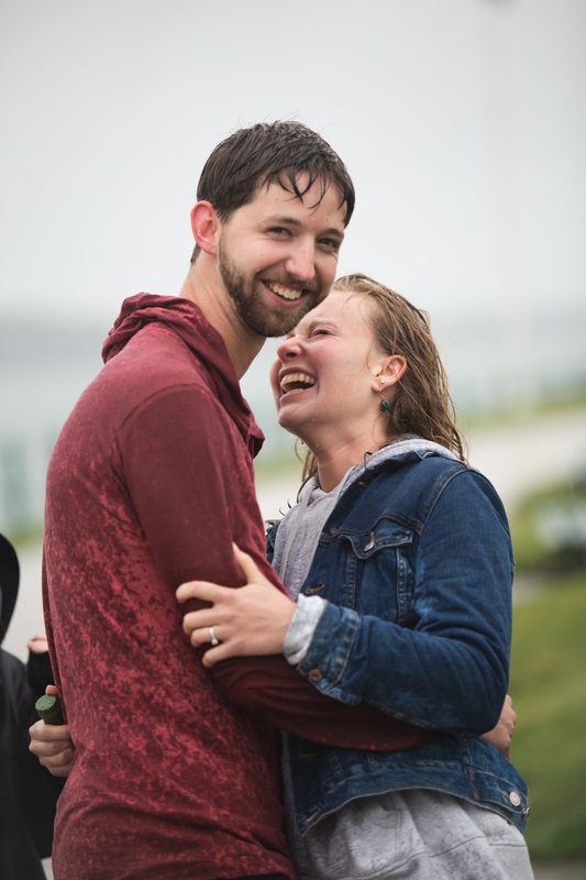 A couple laughs and hugs on a misty, rainy day
