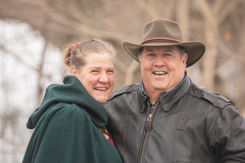 An older couple laughs together, him in a cowboy hat