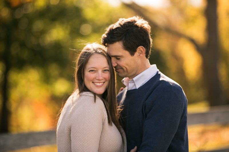 A smiling couple leans close together in warm golden light