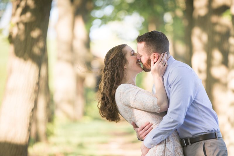 A couple kisses in a sunlit grove of trees