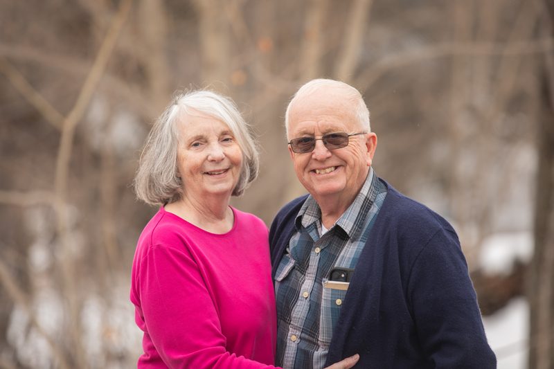 An older couple smiles together, her in a bright pink sweater