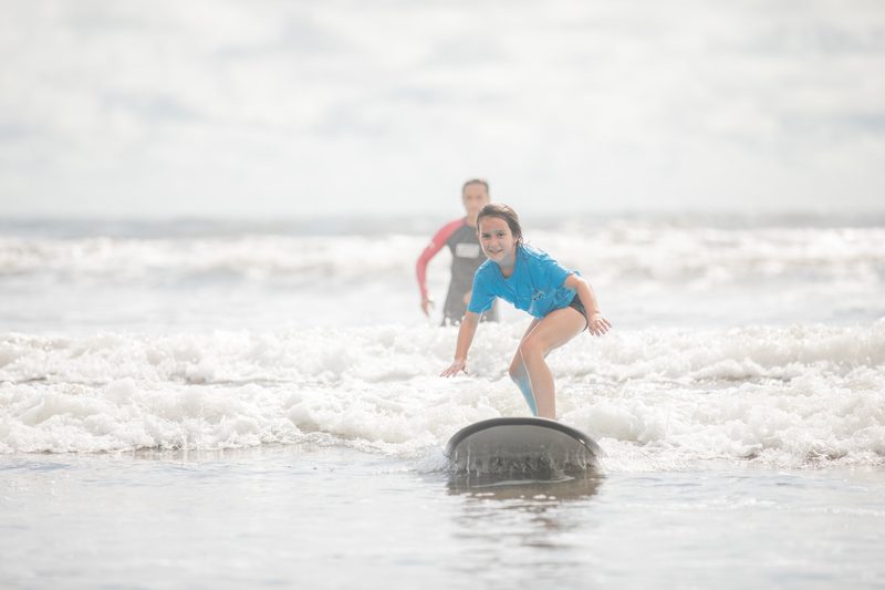 A girl rides a wave on a surfboard