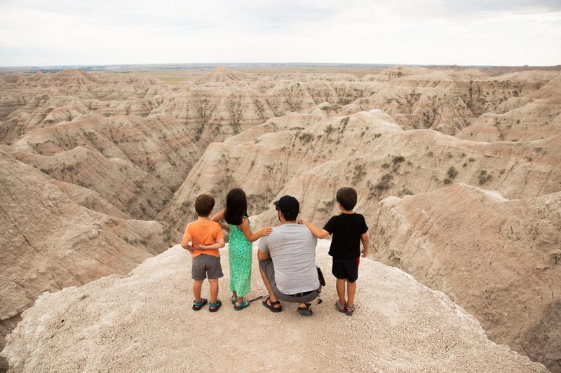 A dad and three kids look out over the Badlands canyons from a ridge